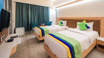 Habitación de hotel con dos camas, un escritorio con computadora, una silla y un televisor.