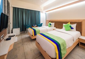 A hotel room with two beds, a desk with a computer, a chair, and a television. - Treebo Sai Rekha Inn (Nashik)