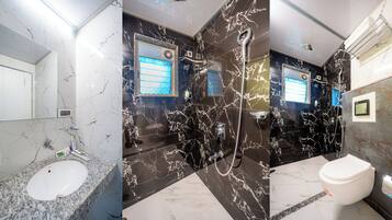 A modern bathroom with a marble sink, a shower with a handheld showerhead, and a toilet.