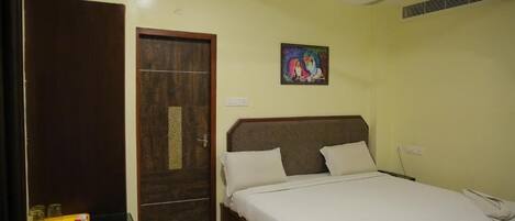 Un dormitorio con cama, armario de madera, ventilador de techo y un pequeño cuadro en la pared.