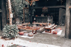 An outdoor dining area with tables set for a meal, surrounded by greenery and decorative elements. - Ekumal Sanctuary (Akumal)