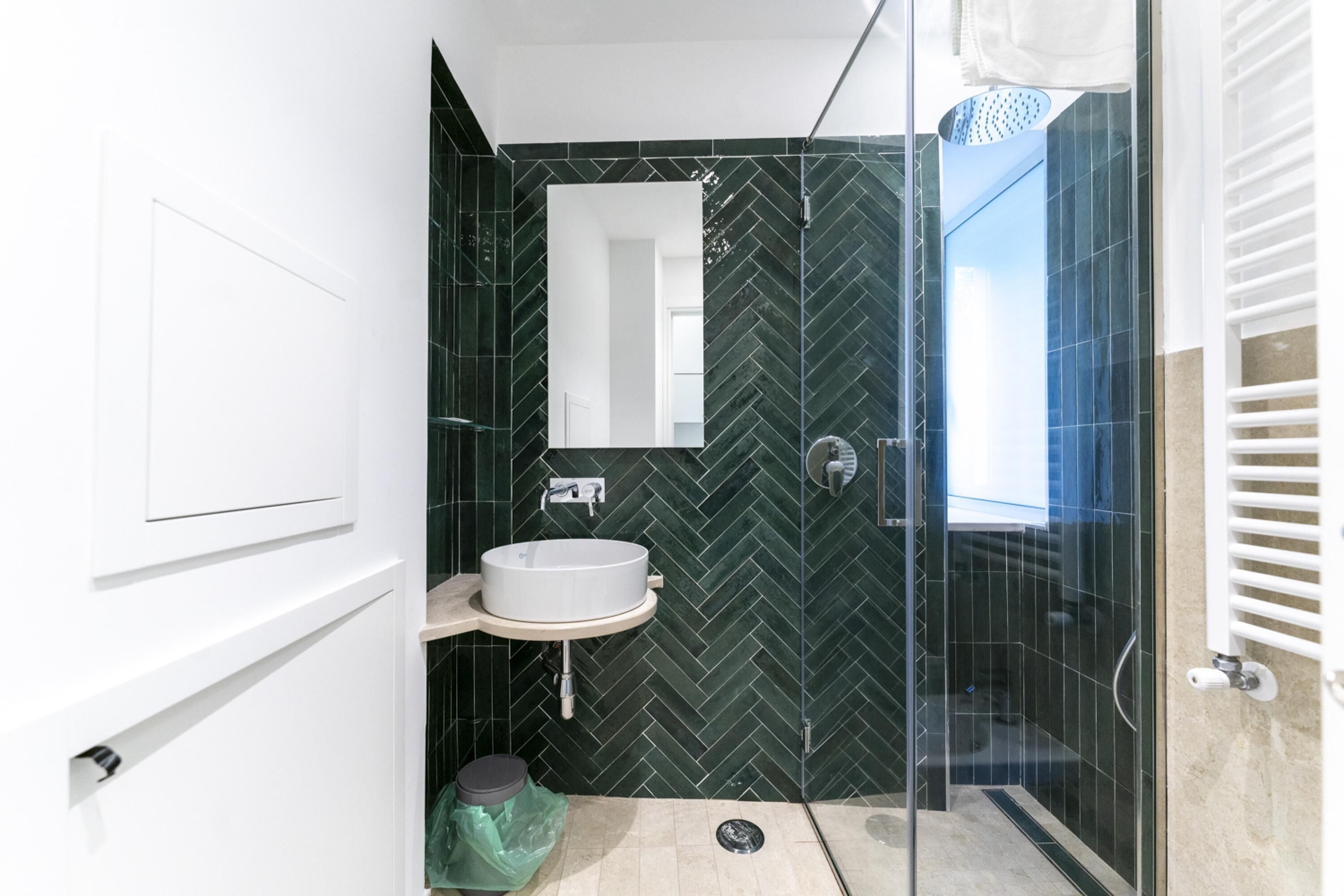 Ein modernes Badezimmer mit einem weißen Waschbecken, einem Spiegel und einer Duschkabine.