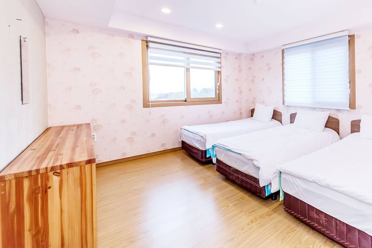Ein Schlafzimmer mit zwei Betten, einem Holztisch und einem Fenster mit Jalousien.