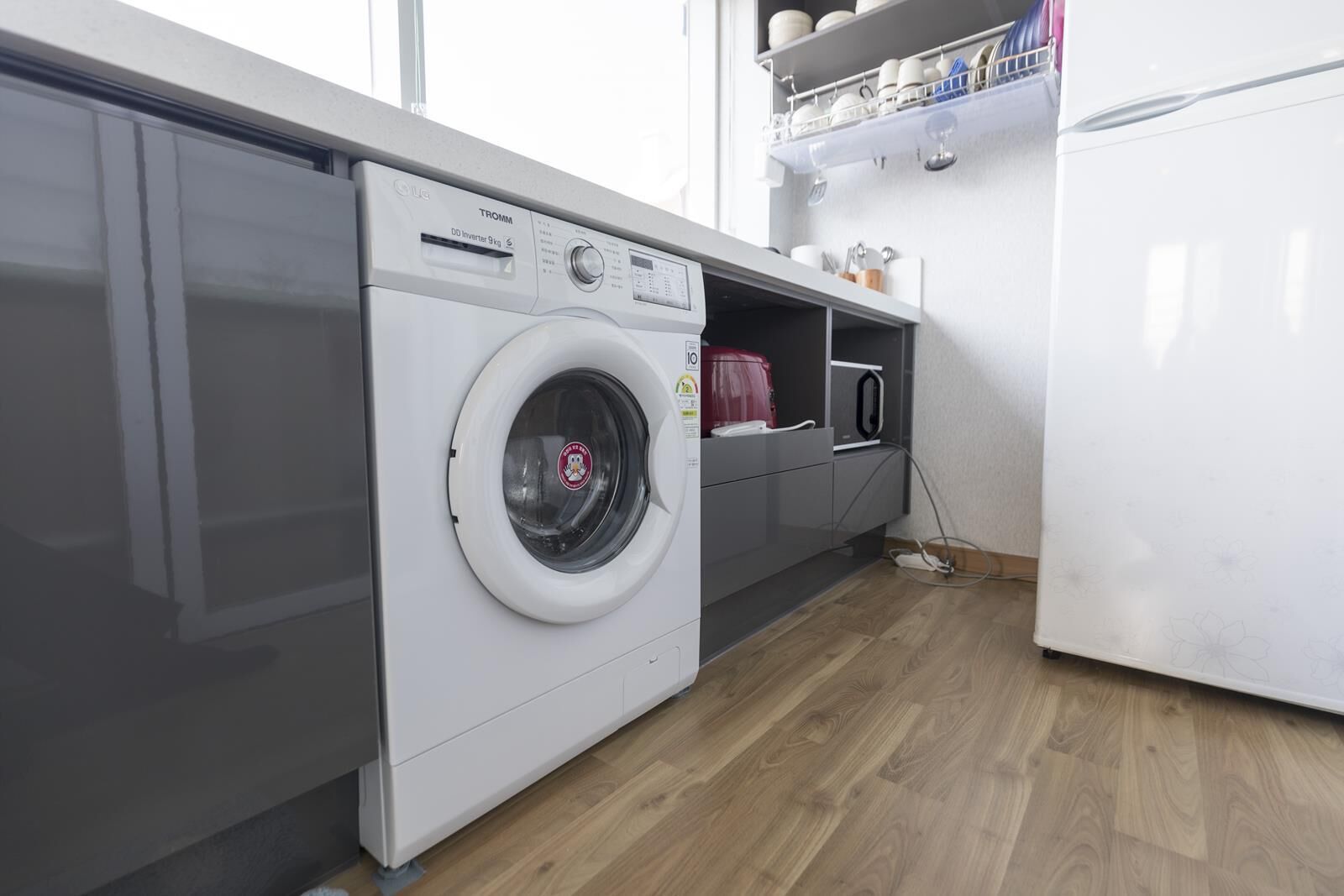 Een functionele keuken met een voorlader wasmachine, een magnetron en een koelkast.