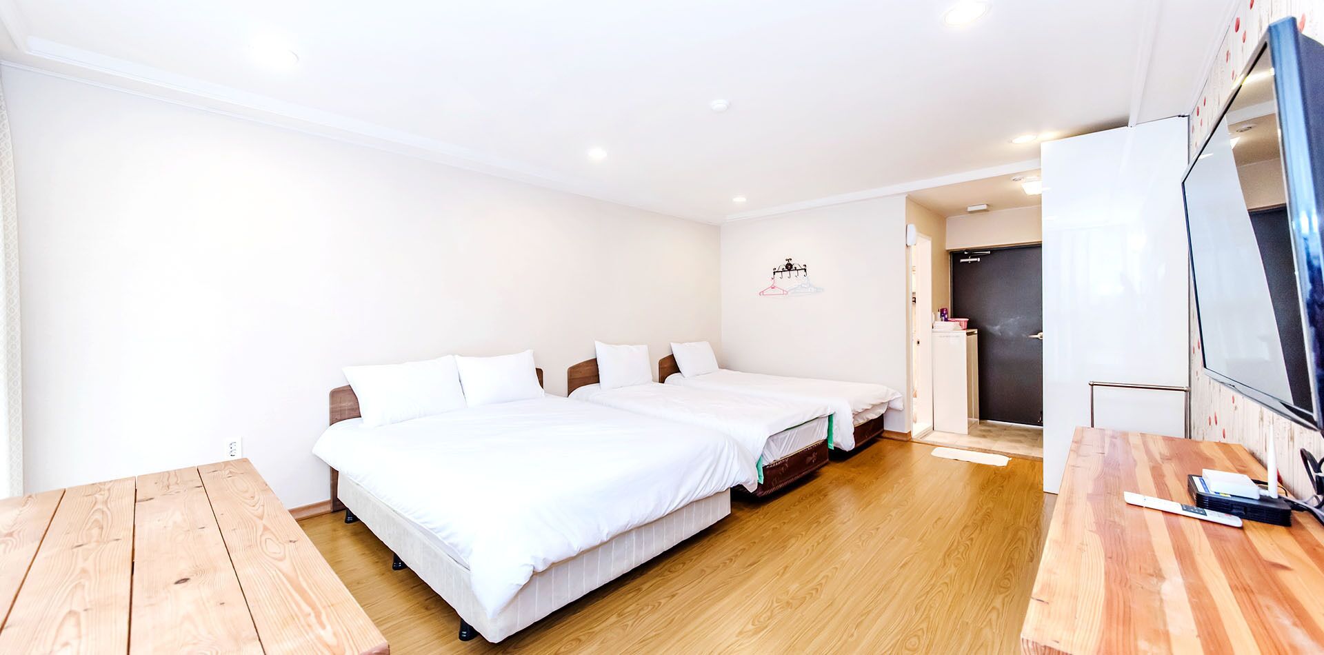 A hotel room with two beds, a wooden table, a TV, and a door leading to a bathroom.