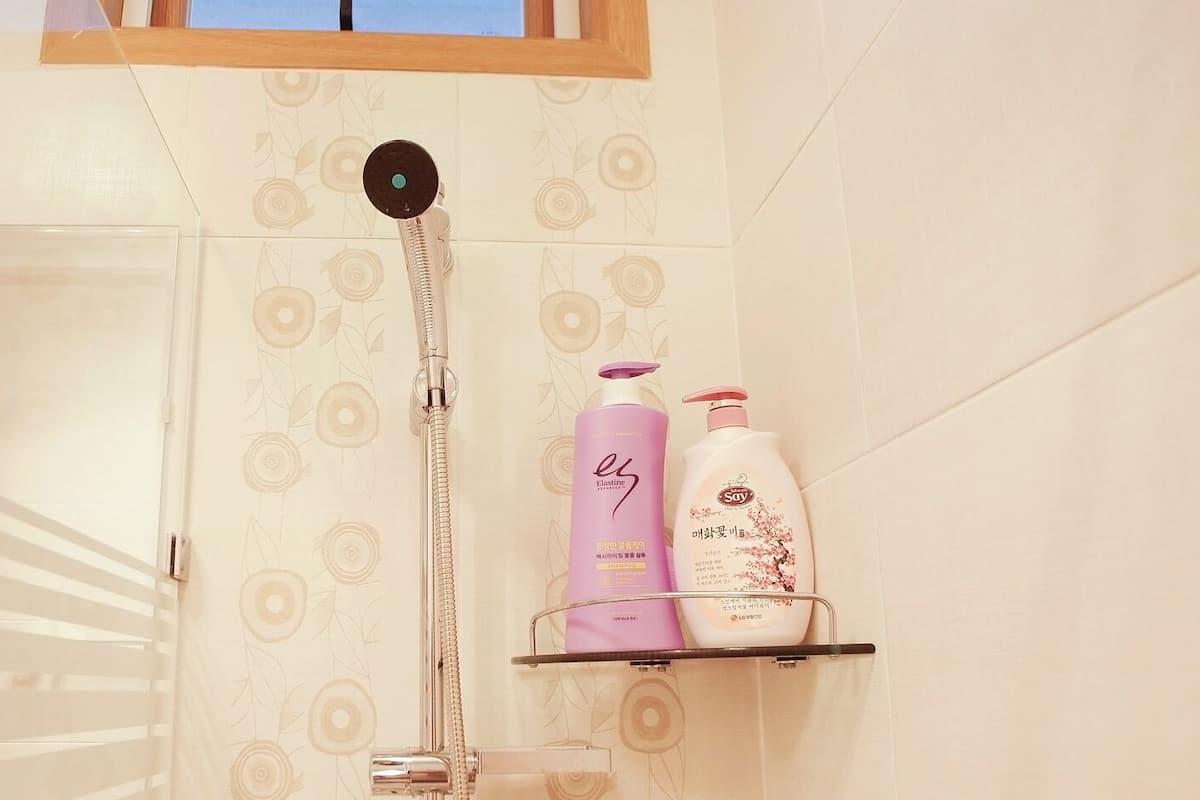 Ein Badezimmer mit Dusche, einer Glasduschkabine und Ablage mit zwei Shampoo-Flaschen.