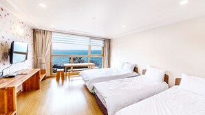 A hotel room with two beds, a desk, a TV, and a view of the sea. - Aerang and Baebijang's House (Jeju City)