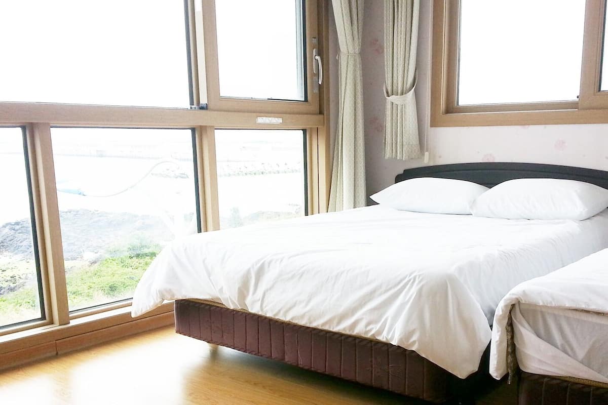 Ein Schlafzimmer mit zwei Betten, großen Fenstern und Blick auf eine felsige Landschaft.