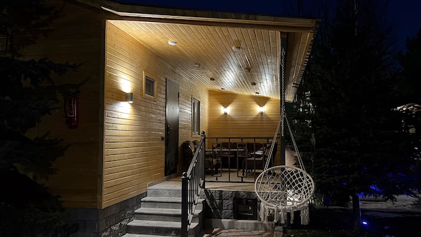 Une cabane en bois dotée d’un porche couvert, d’un extincteur et d’une chaise suspendue.