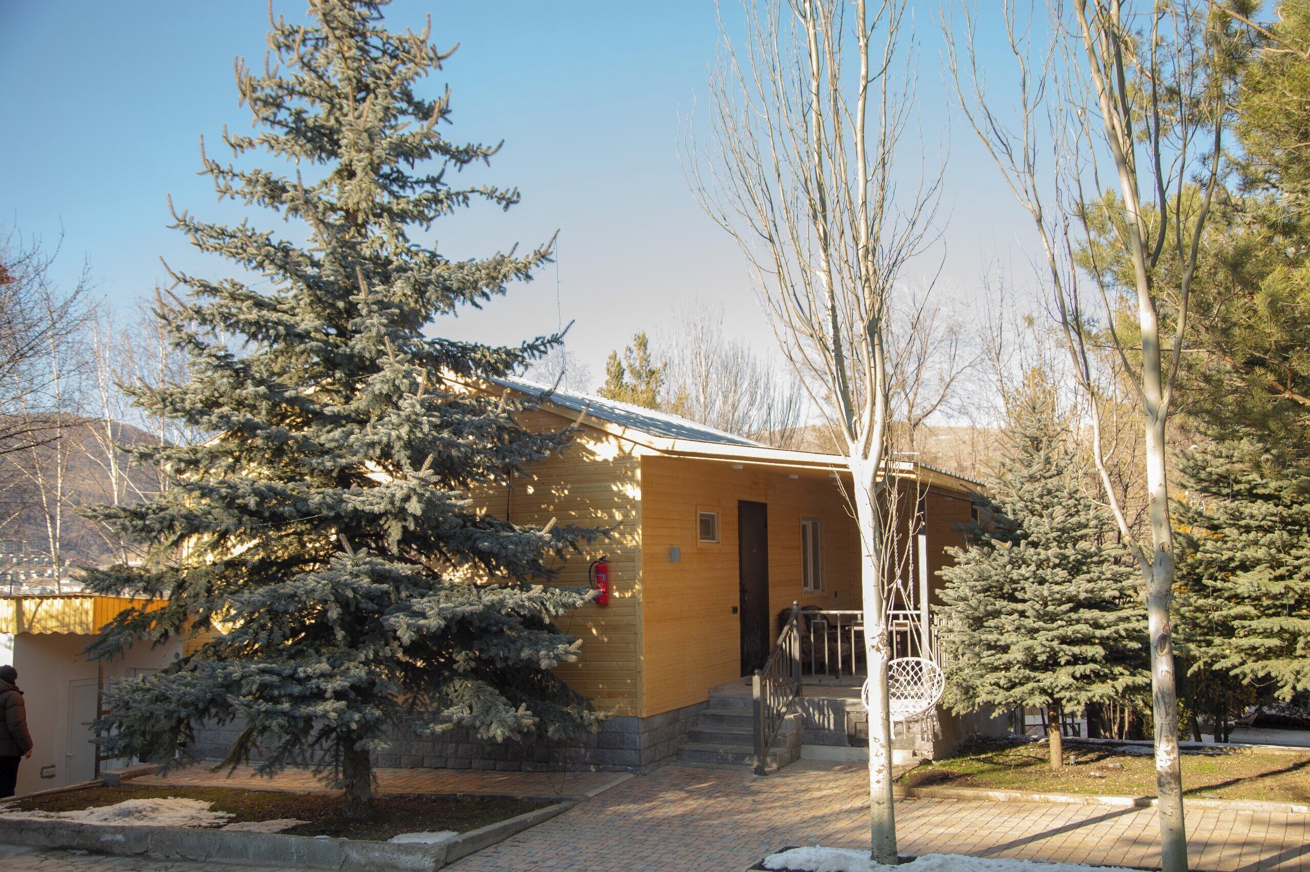 A building with a wooden exterior, a door, and a small porch with a railing.