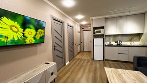 Une cuisine moderne équipée d’un four à micro-ondes, d’un évier et d’un réfrigérateur. On aperçoit une table à manger et des chaises au premier plan.