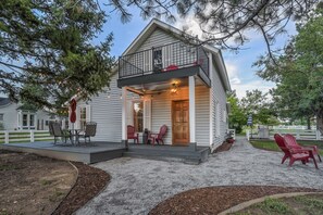 A house with a porch, outdoor seating, and a fenced yard.