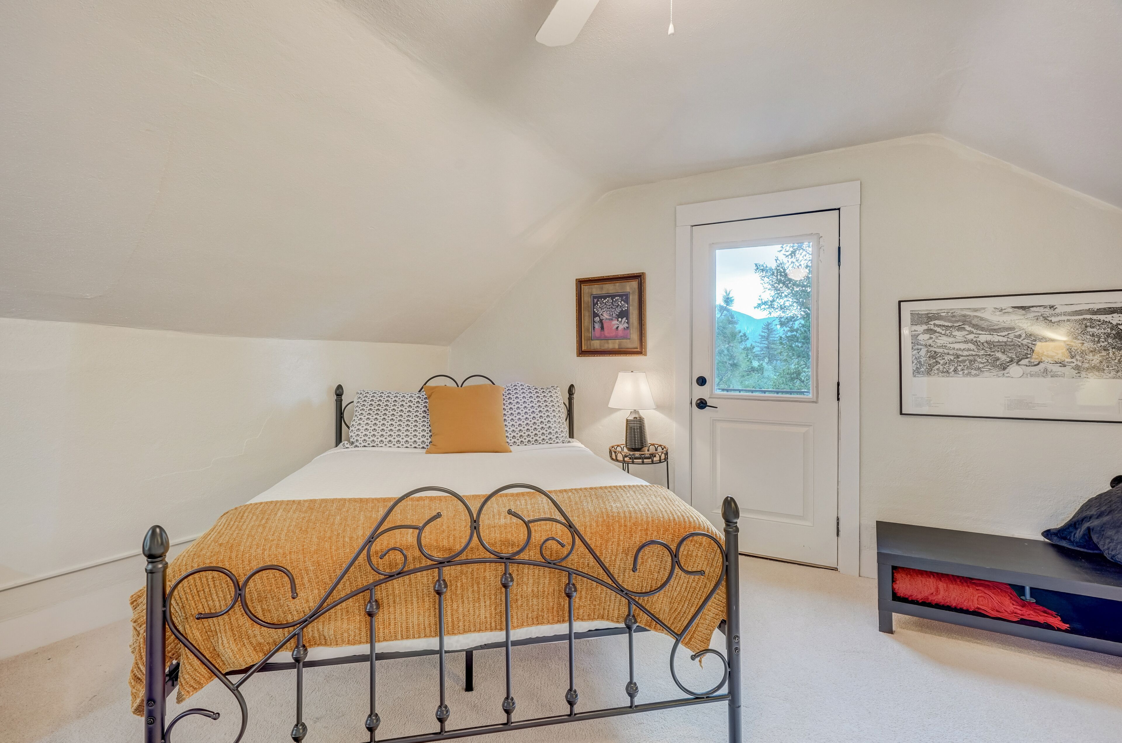 A bedroom with a bed, bedside lamp, and a bench.