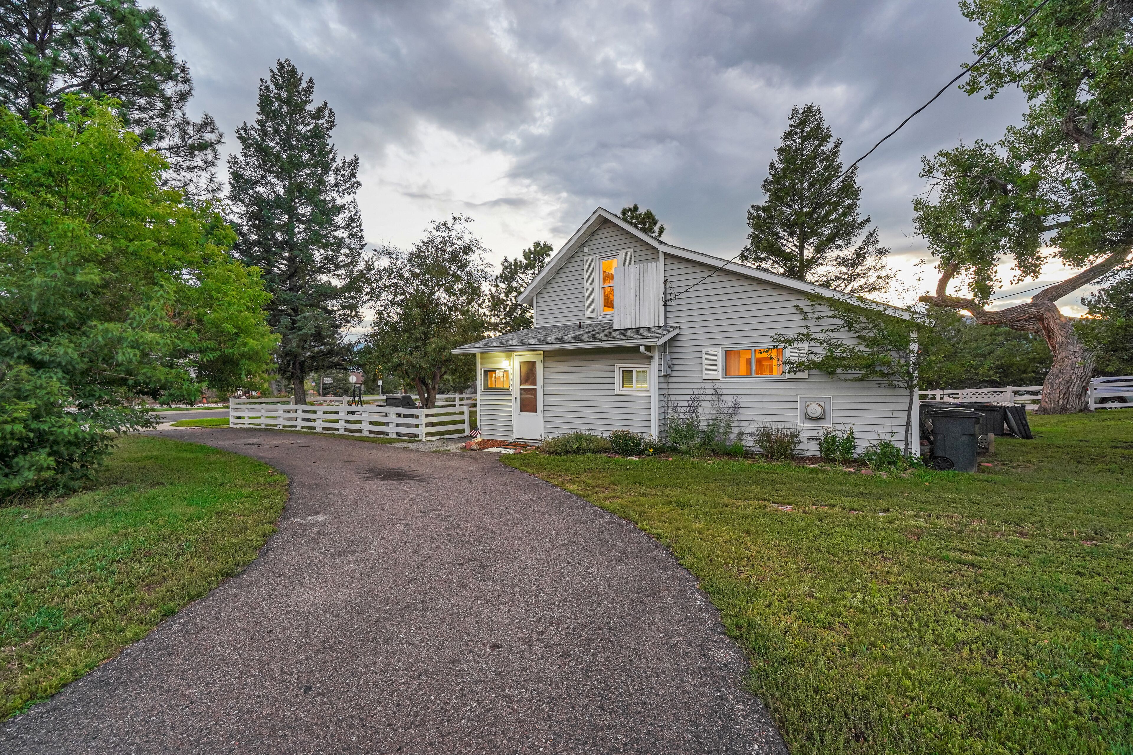 A single-story house with a gravel driveway leading to a white fence.
