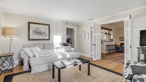 A modern living room with a sofa, coffee table, and a dining area visible through an open door. - Bluebird Inn (Monument)