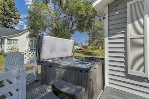 Un jacuzzi con banco, cubierta de madera y cerca blanca.