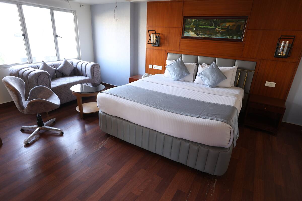 Una habitación de hotel con una cama grande, un sofá, una silla y una pequeña mesa.