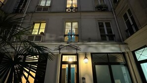 Un immeuble à plusieurs étages doté d’une entrée centrale, de grandes fenêtres et d’un escalier menant à l’entrée.
