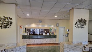 A reception area with a counter, seating, and decorative wall art. - Castle Harbour 3 (Los Cristianos)