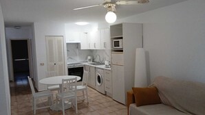 A compact kitchen with a dining area, a washing machine, and a microwave. - Castle Harbour 3 (Los Cristianos)