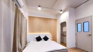 A modern bedroom with a large bed, a wooden headboard, and a door with two windows.
