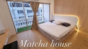 A Matcha house bedroom with a bed, curtains, and a view of buildings.