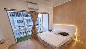Dormitorio de Matcha House con cama, cortinas y vistas a edificios.
