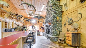 Een rustiek interieur met een stenen openhaard, houten plafond en een bar met krukken.