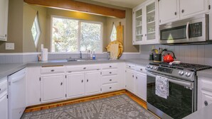 Una cucina con mobili bianchi, un piano cottura in acciaio inossidabile e un forno a microonde.