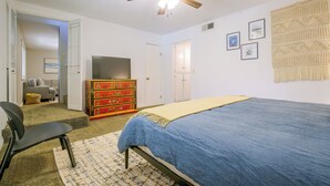 Una camera da letto con un letto, una cassettiera, una televisione e una ventola a soffitto.