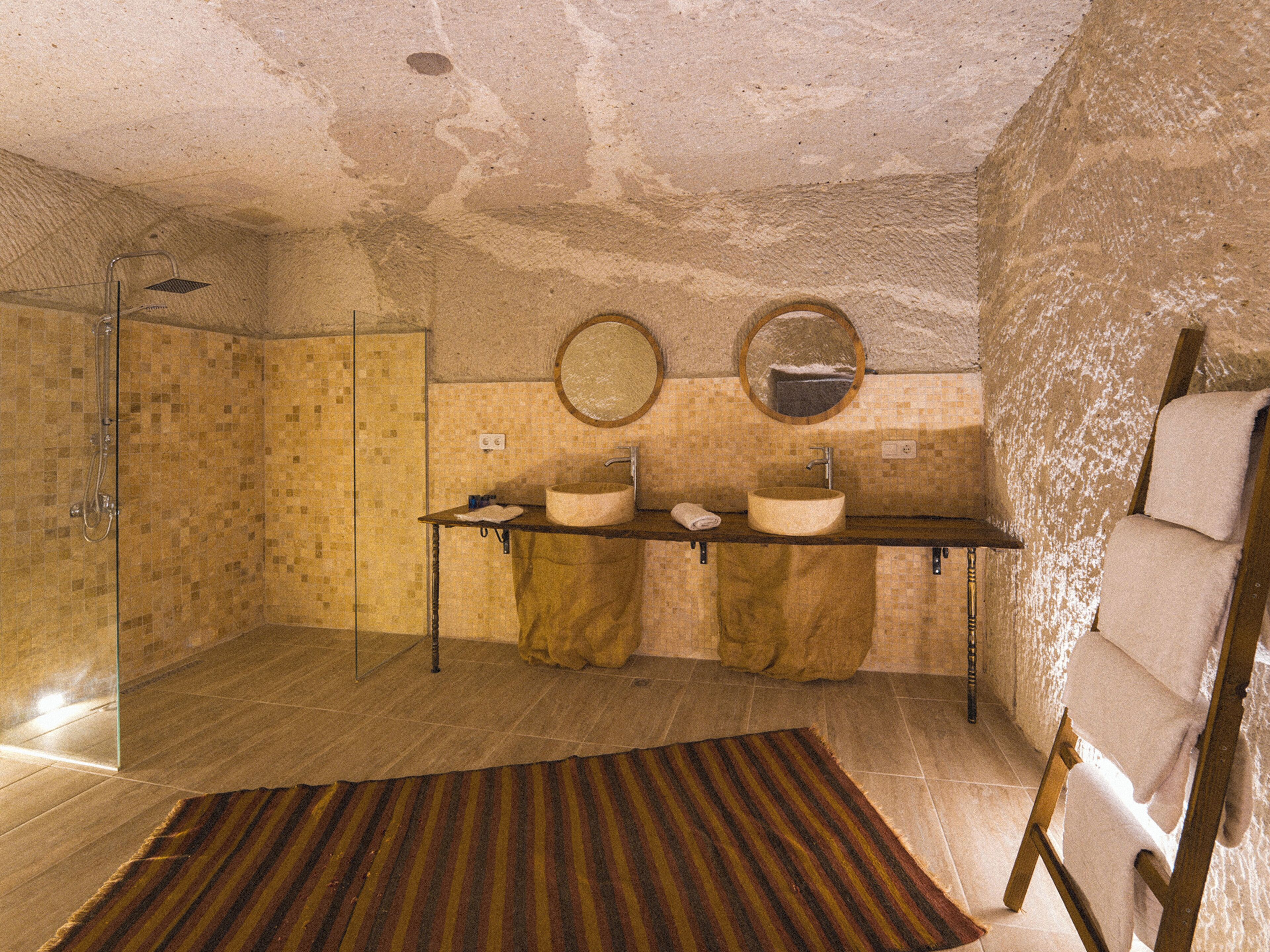 A bathroom with a shower, two sinks, and a mirror.