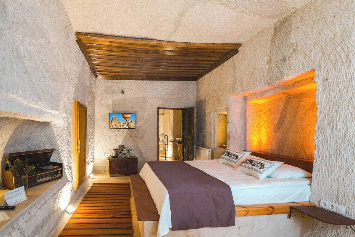 A cozy room with a bed, wooden bench, and a stone wall.