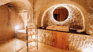 A spa room with a wooden bench, a circular window, and a shower area. - MY CAVE SUITE (Nevsehir)