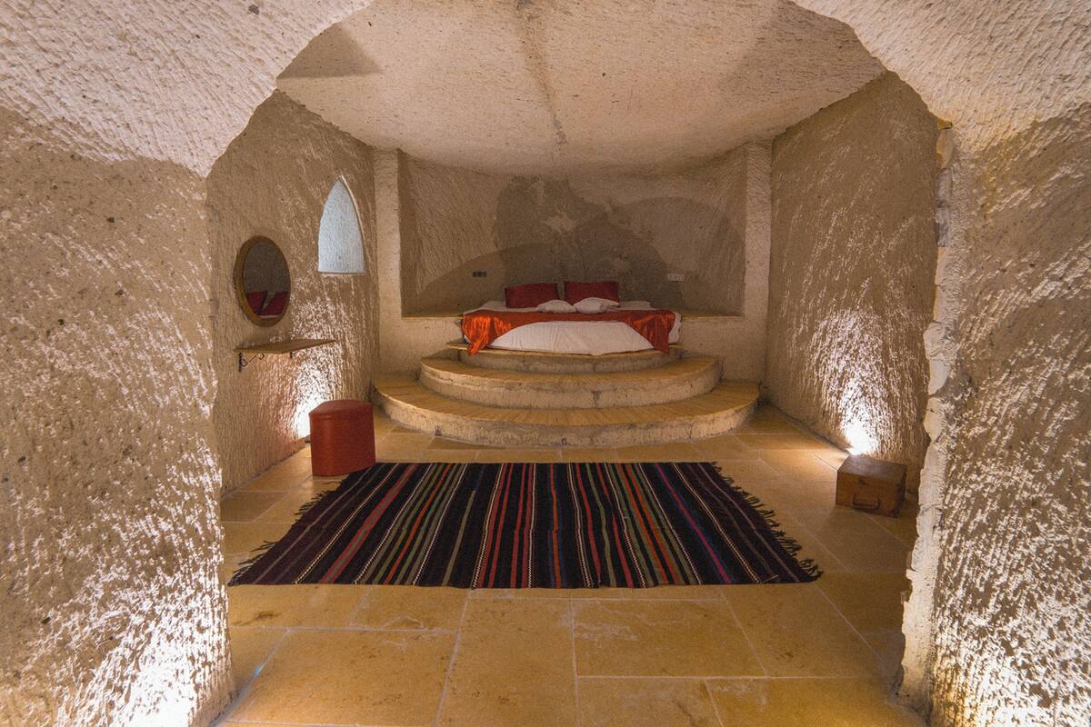 A room with a bed, a small window, and a rug.
