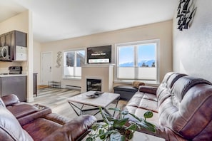 A modern living room with a leather sofa, a coffee table, and a flat-screen TV displaying a welcome message.