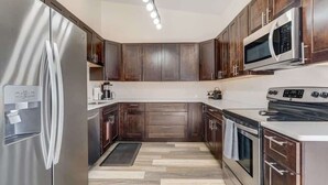 Een moderne keuken met donkerhouten kasten, roestvrijstalen apparatuur en een vloer in een lichte kleur.