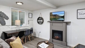 Una sala de estar moderna con chimenea, un comedor y un televisor montado en la pared.