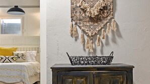 Una habitación con un mueble de madera oscura, un tapiz estampado y una cesta con forma de bicicleta en la parte superior.