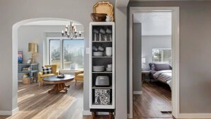 Uma sala de estar moderna com uma estante embutida, um espaço de refeições com uma mesa redonda e um ambiente aconchegante para sentar.
