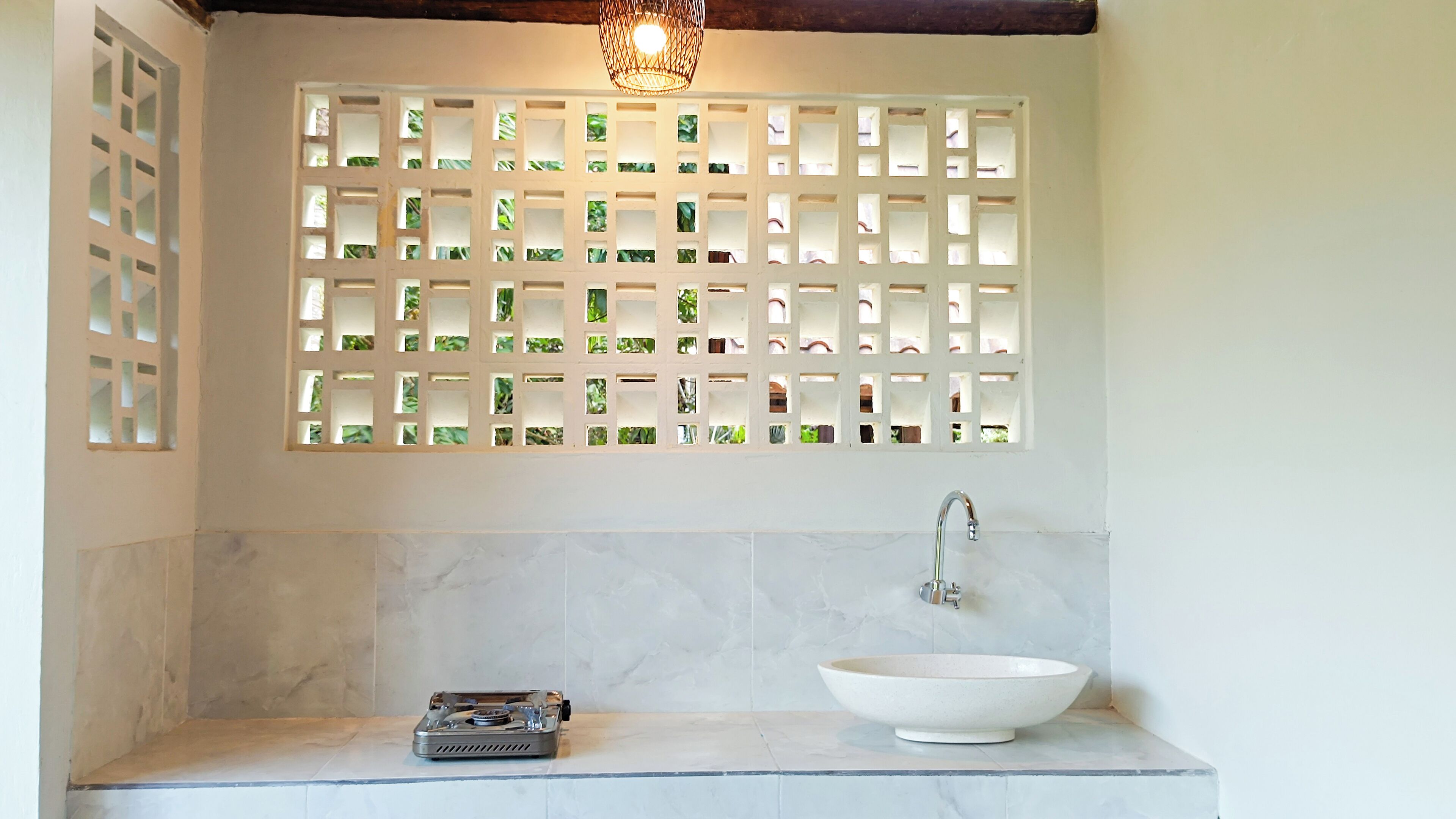 A bathroom with a white sink, a gas stove, and a decorative wall with a grid pattern.