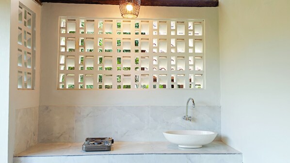 A bathroom with a white sink, a gas stove, and a decorative wall with a grid pattern.