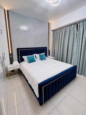 A modern bedroom with a large bed, a bedside table, a nightstand, and a window with curtains. - Lux High Rise Marina Apartment (Dubai)