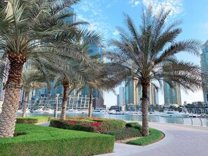 A waterfront promenade with palm trees and a marina. - Lux High Rise Marina Apartment (Dubai)
