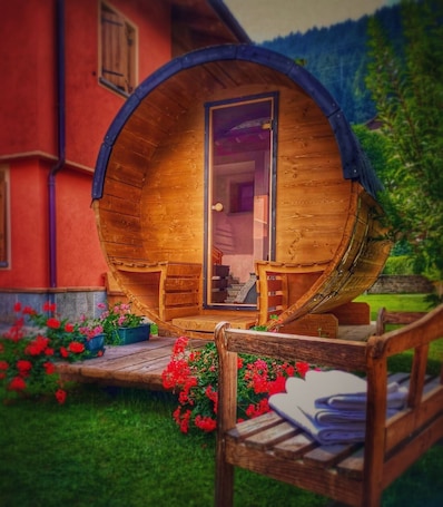 A wooden barrel-shaped structure with a door, two chairs, and a small table outside.. Holiday Apartment "Casa Clus Bormio 2" with Mountain View, 2 Balconies & Wi-Fi