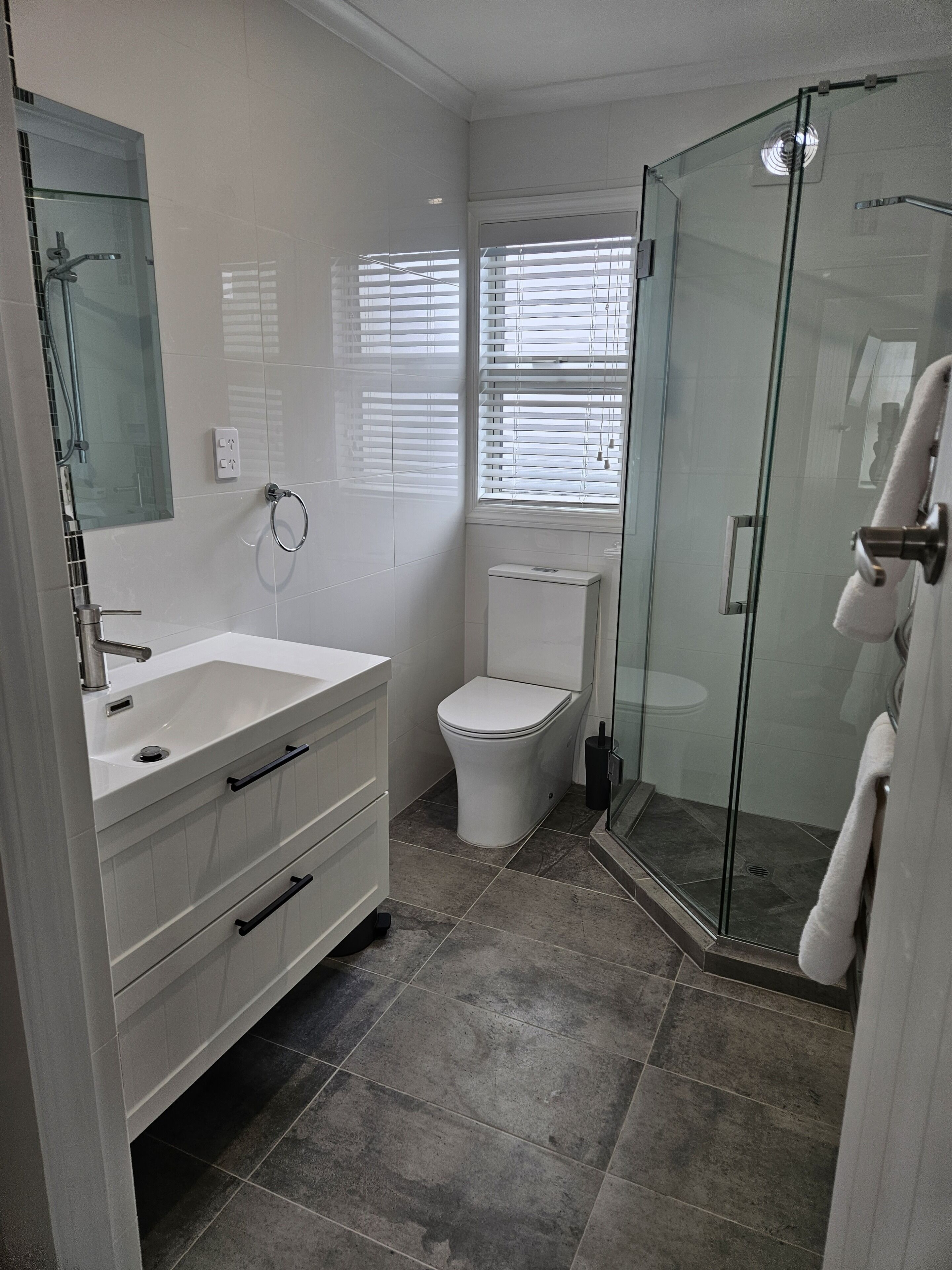 A modern bathroom with a glass shower enclosure, a white sink, and a toilet.