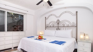A neatly made bed with a white bedspread, a decorative headboard, and bedside lamps. - Amazing ocean view from Estrellita de Mar 303 2BD Condo for rent in Amapas, Puer (Puerto Vallarta)