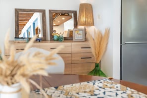 A kitchen with wooden cabinets, a stainless steel refrigerator, a mirror, and a lamp.
