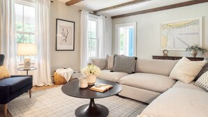 Una sala de estar con sofá, mesa de centro, lámpara y ventana con cortinas.