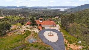 A house with a red-tiled roof, surrounded by a landscaped garden and a winding driveway. - 20-Acre Retreat • Hot Tub + Panoramic Views + Pickleball Court | Slice of Heaven (Temecula)