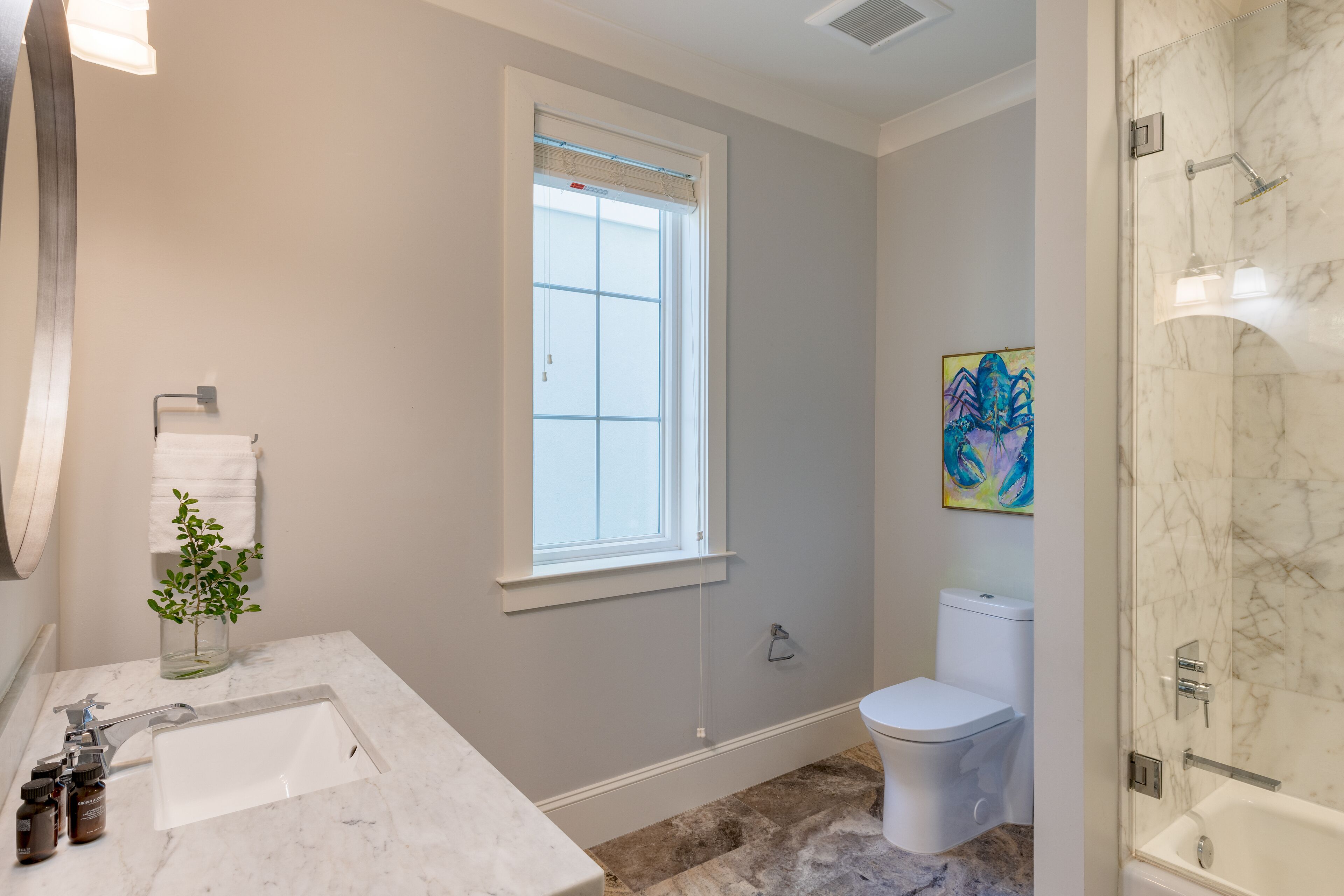 A bathroom with a marble sink, toilet, and shower.